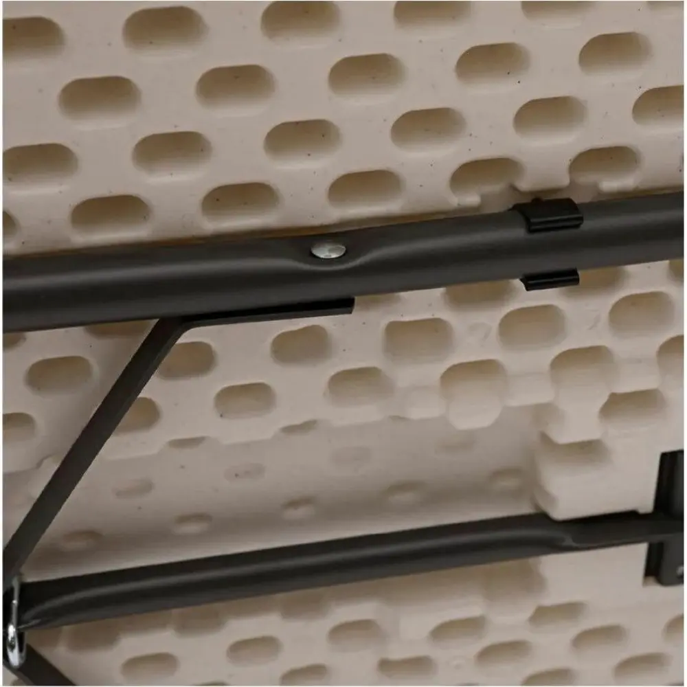 Underside view of a folding table showing the central locking mechanism and perforated surface