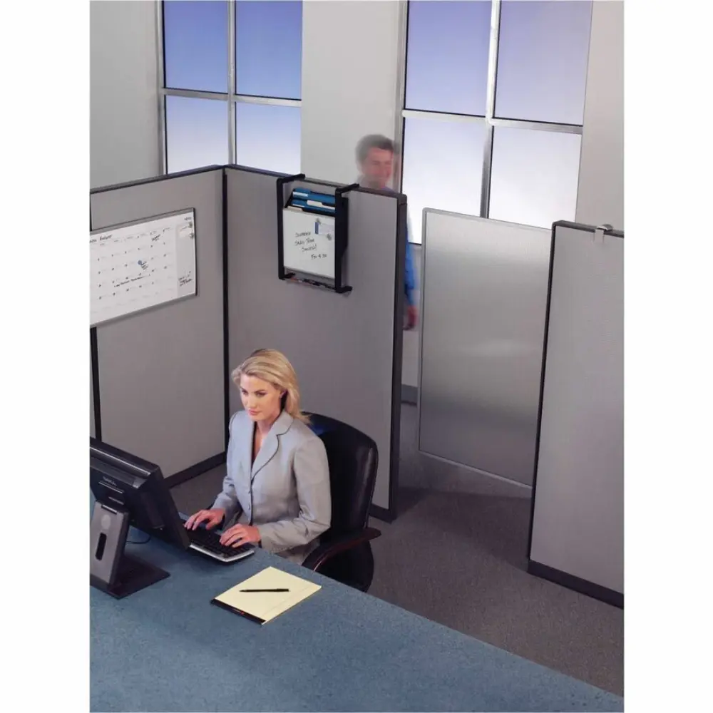 Person in red sweater standing near a whiteboard in an office cubicle row