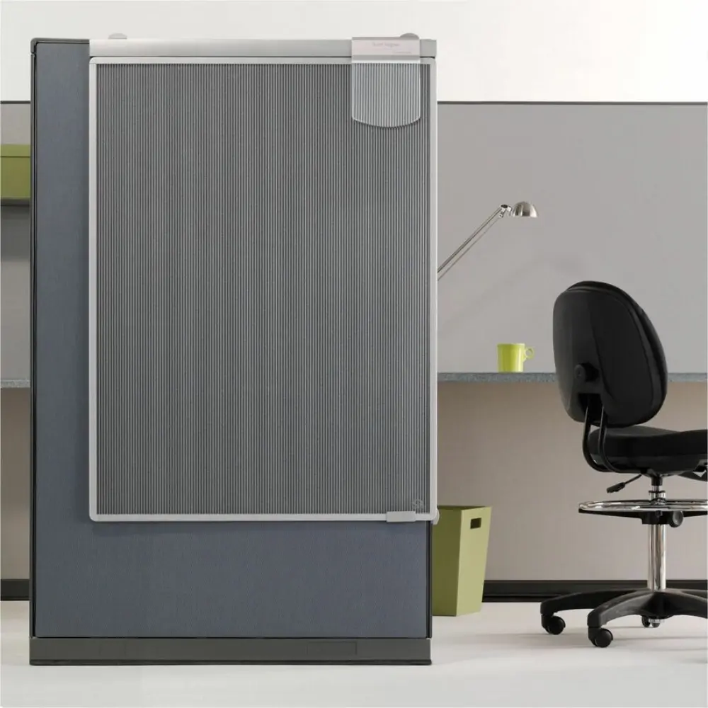 Businesswoman in black suit standing between two tall cubicle panels with glass door