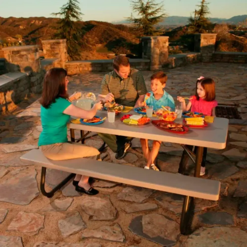 Picnic table set for an outdoor meal on stone patio at sunset
