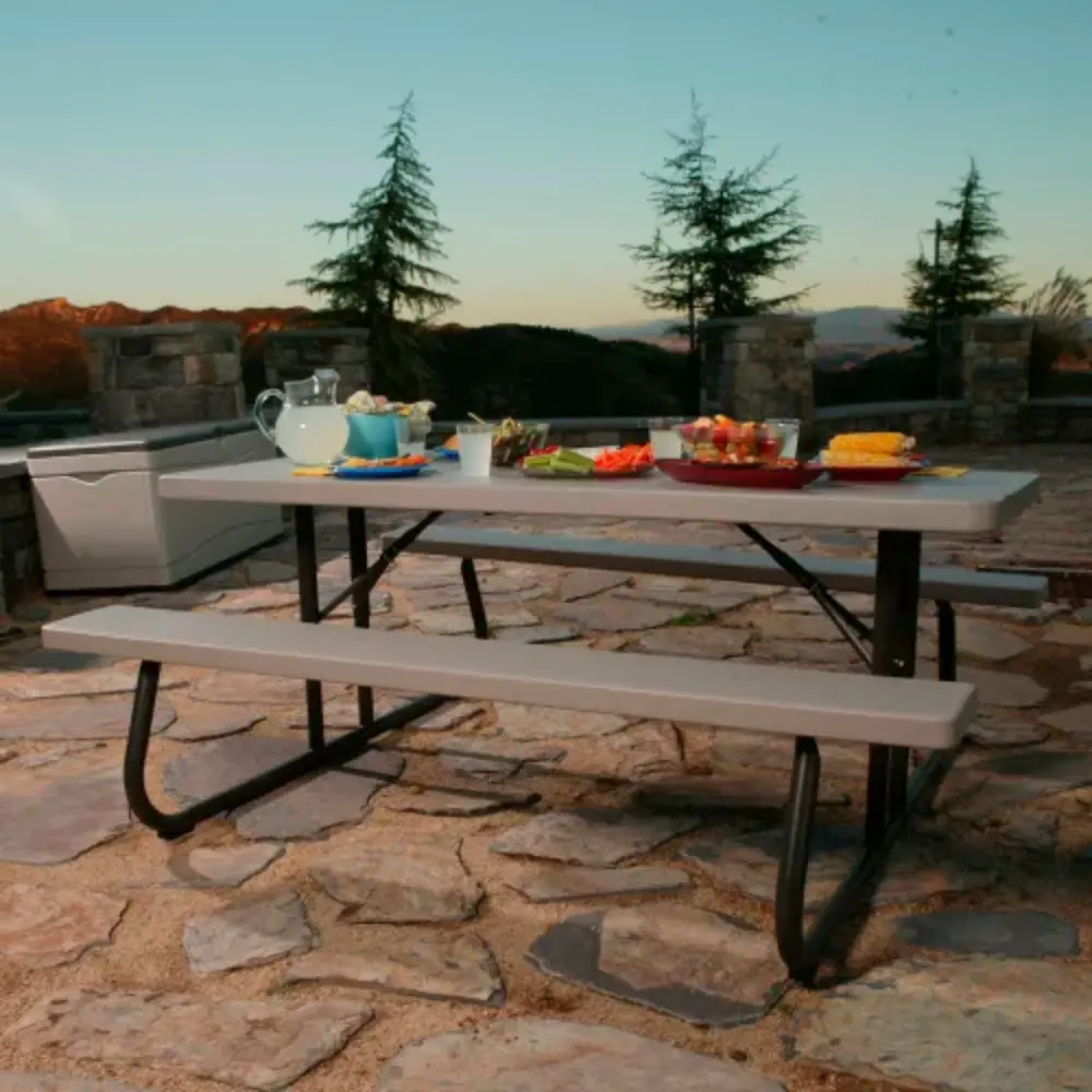 Picnic table with a long serving setup on a stone patio at sunset