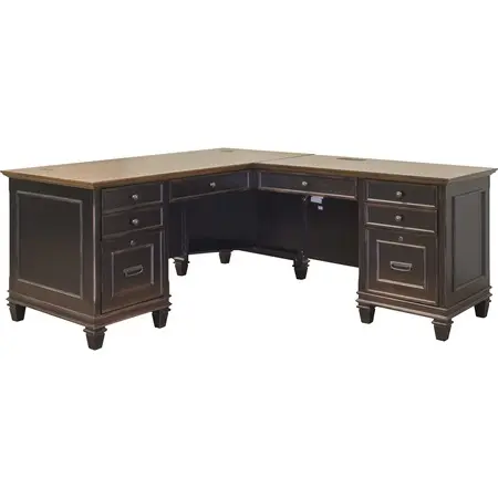 A large black wood executive desk with numerous drawers and a wooden top in a modern industrial room with a brick wall.