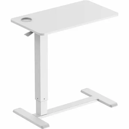 A small white standing desk with a tray-like top and a sofa in the background, showing a home living room scene