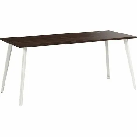 A modern office desk with dark wood top and white angled legs, set in a bright office with chair and cabinets in background.